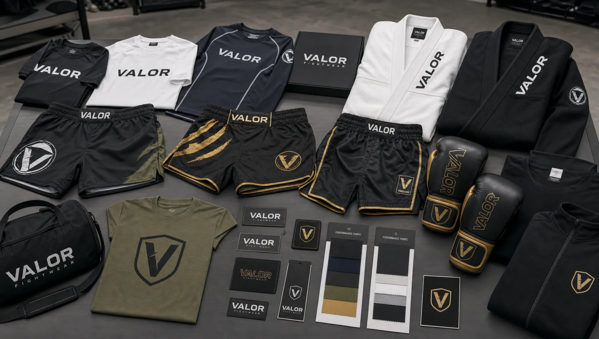 A clean studio layout of custom combat sports apparel including MMA shorts, rash guards, boxing apparel, BJJ gis, and branded gym wear arranged on a table with fabric swatches and label samples nearby.
