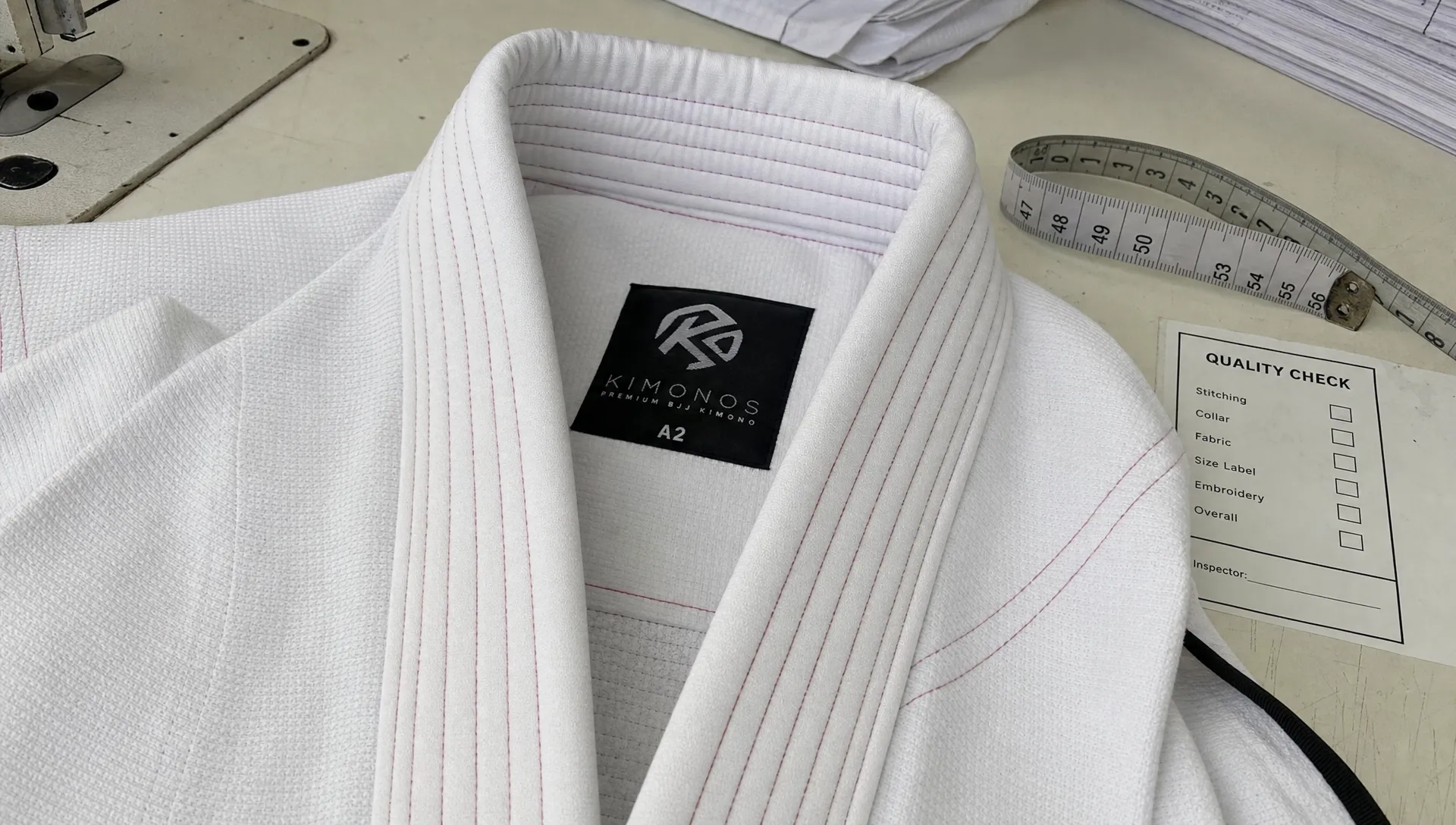 A close-up of a BJJ gi collar and stitching on a sewing table during quality inspection.