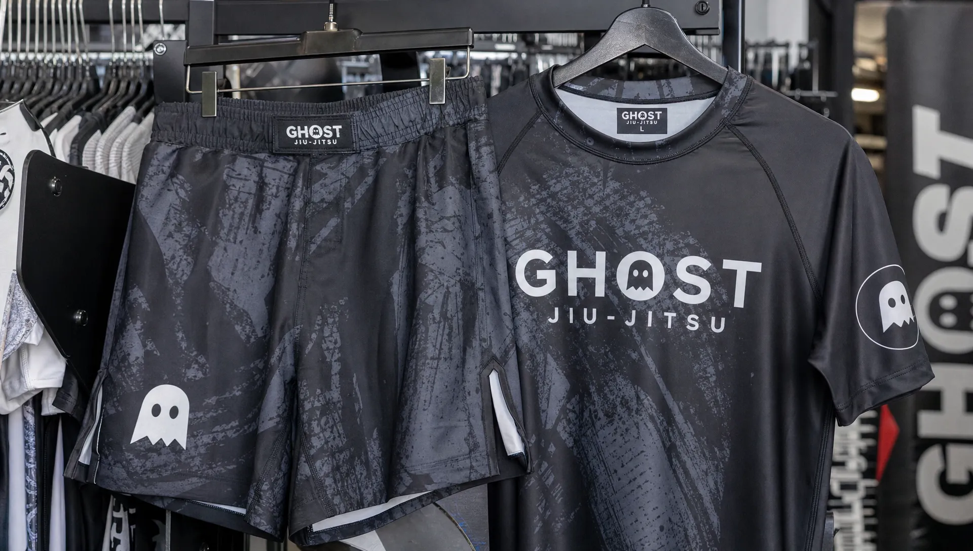 Branded fight shorts and a rash guard hang on a gym retail rack near the checkout area.