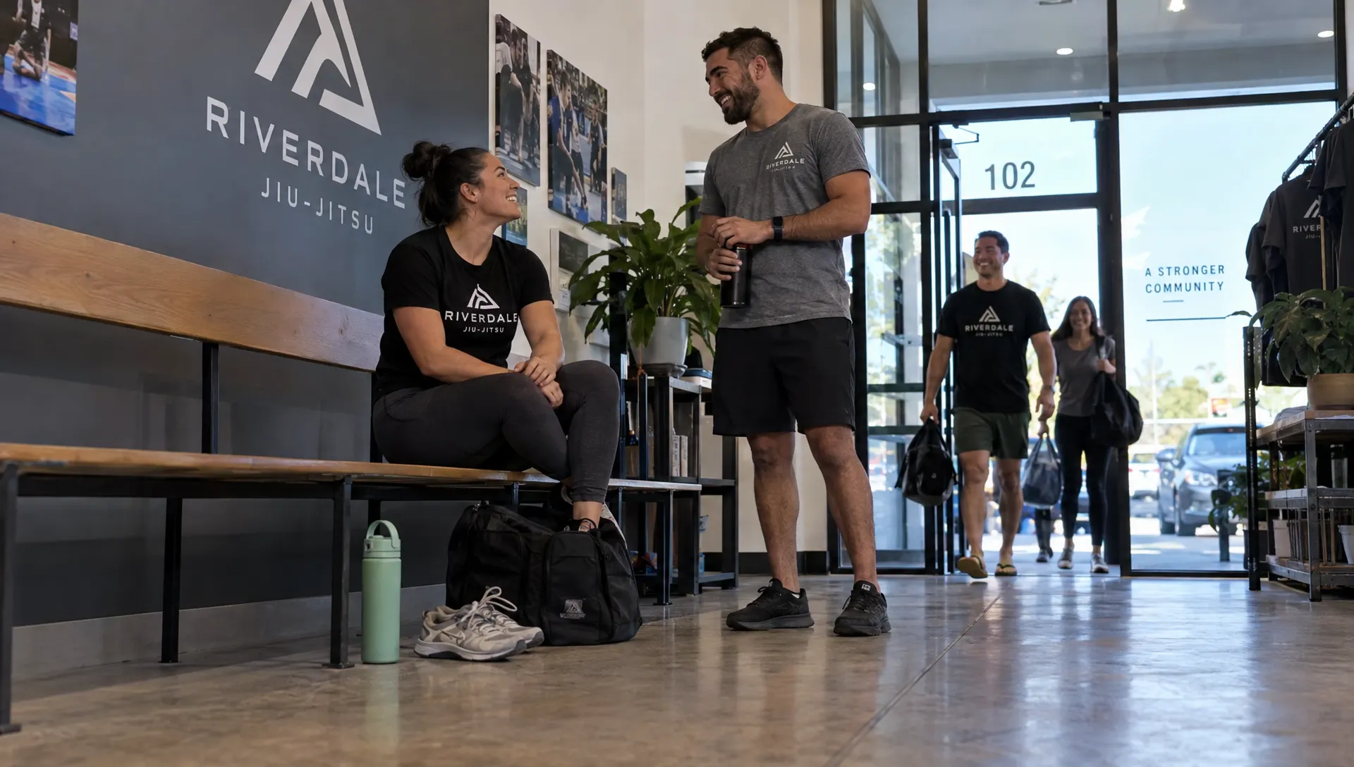 A gym member wears a team T-shirt in the lobby after training, with other members heading out in the background.