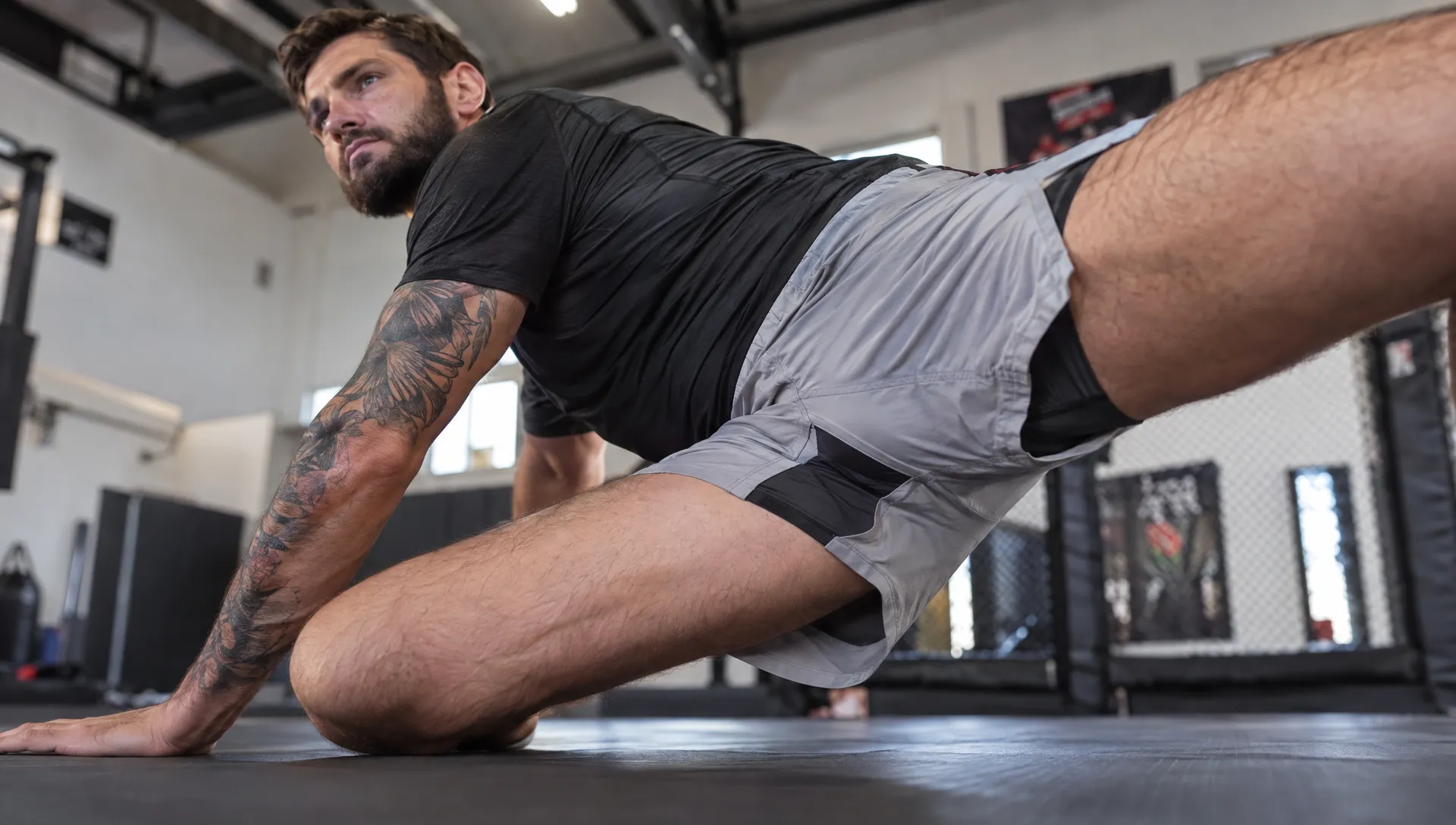 Fightwear shorts stretch across an athlete’s hip during a deep lunge, showing how the gusset and seams move during training.
